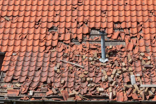 Damaged red clay roof tiles with multiple broken and cracked sections