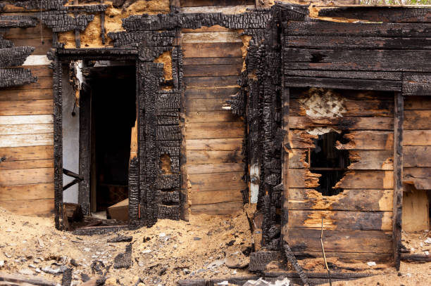 Charred wooden building with burned walls and holes, remnants of fire damage