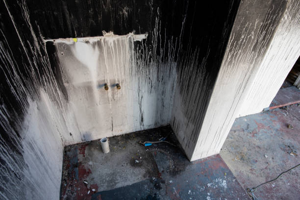 Weathered, stained shower stall with dripping water and worn surfaces