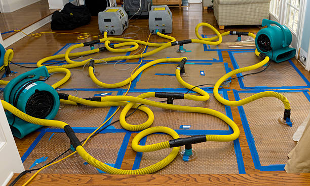 Water damage restoration equipment with yellow hoses and blue tape on floor