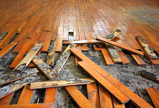 Damaged wooden floor with broken and scattered planks and debris