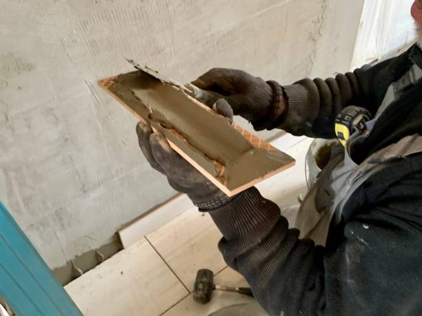 Worker using trowel to apply plaster or mortar on wall