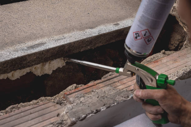 Hand holding pliers near damaged concrete and brick construction site