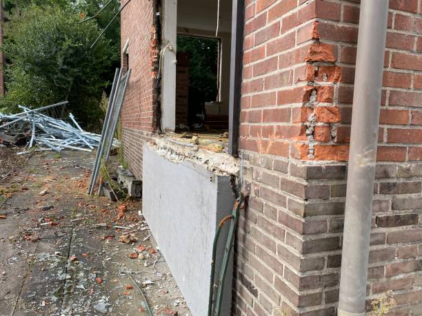 Damaged brick building with cracked wall and construction debris outside