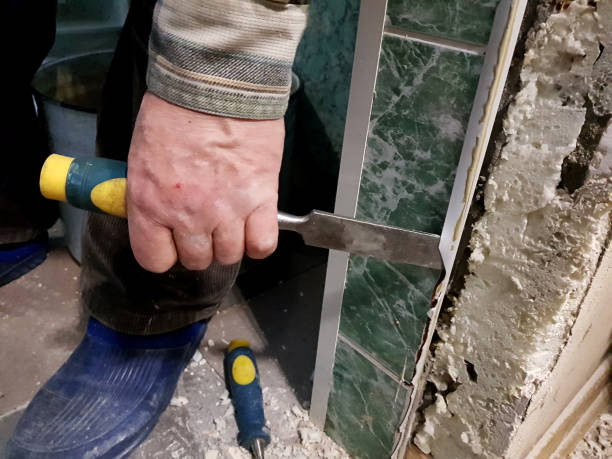 Hand holding chisel during tile removal or renovation work