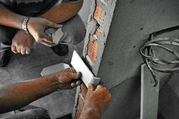 Construction worker applying plaster to wall with trowel and cement