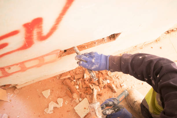 Worker using chisel and gloves to break or remove construction material