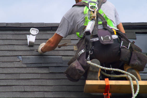 Roofer with safety harness working on shingles with tools and equipment