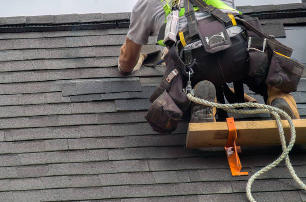 Roofer with safety harness installing shingles on a steep roof