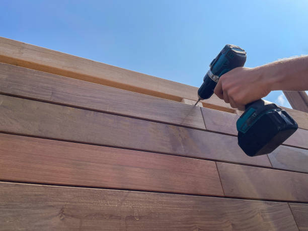 Hand using cordless drill to install wooden deck boards