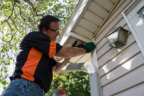 Worker in orange and black shirt repairing outdoor light fixture