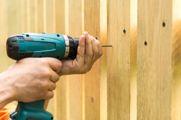 Teal cordless drill screwing a screw into wooden planks