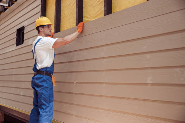 Construction worker installing siding on house exterior wearing hardhat