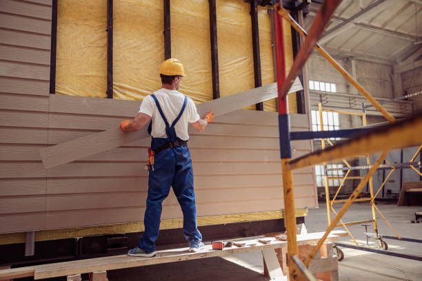 Construction worker in hard hat installing siding on building interior