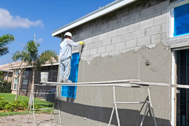 Worker in white protective suit applying stucco to exterior wall