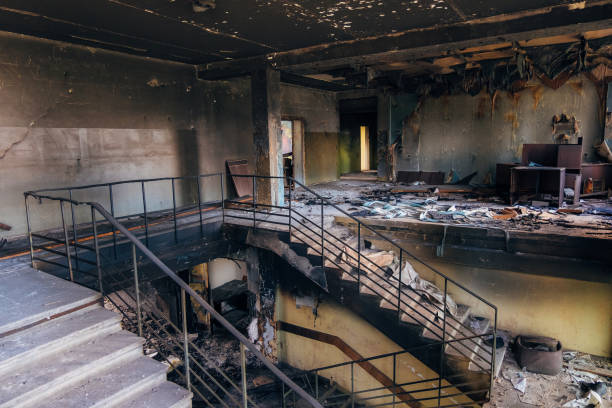 Abandoned, damaged interior with metal stairs and debris scattered across floor