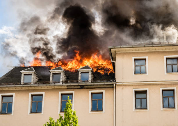 Intense fire engulfing the roof of a residential building with thick black smoke