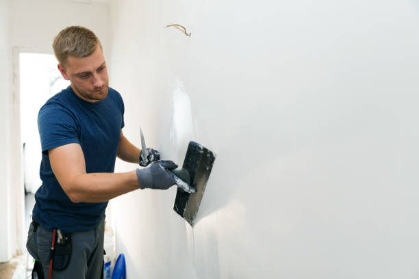 Worker smoothing wall with plastering tool in interior renovation