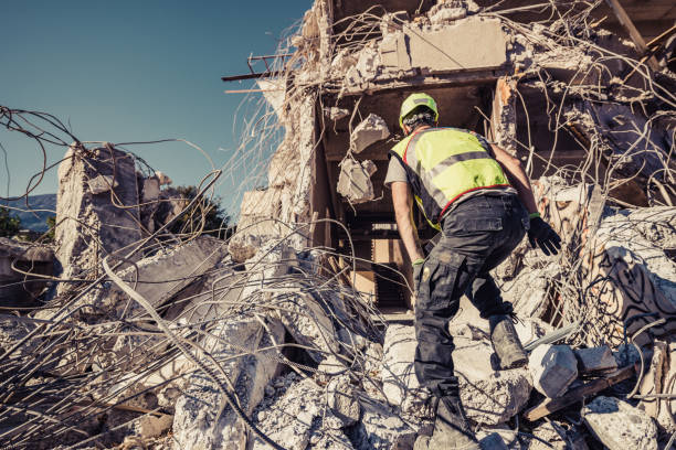 Construction worker searching through collapsed building debris after disaster