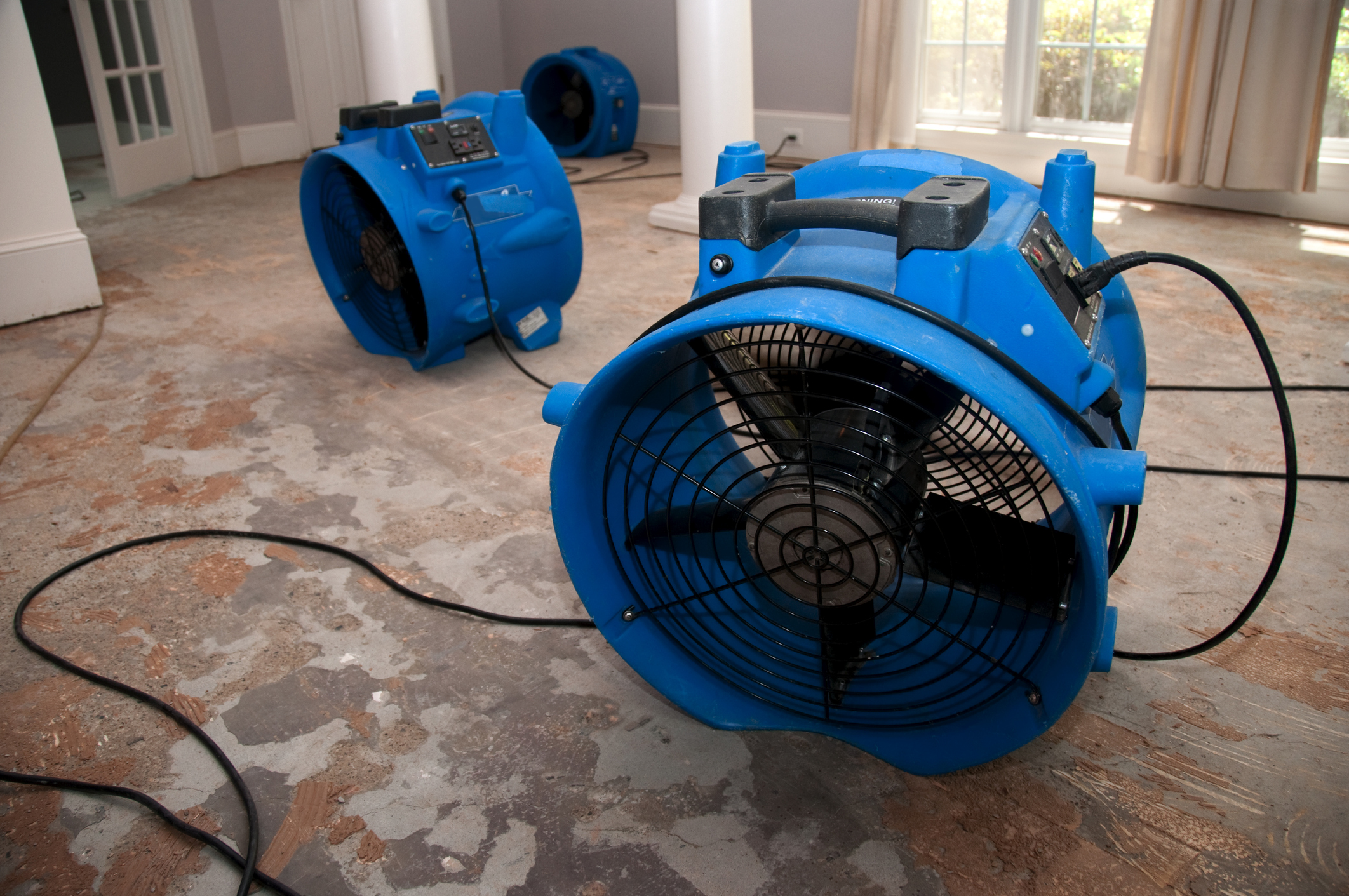 Blue industrial fans on concrete floor for water damage restoration