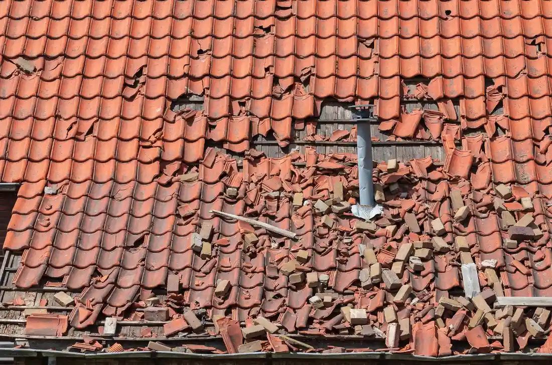 Damaged red clay roof tiles with multiple broken and cracked pieces