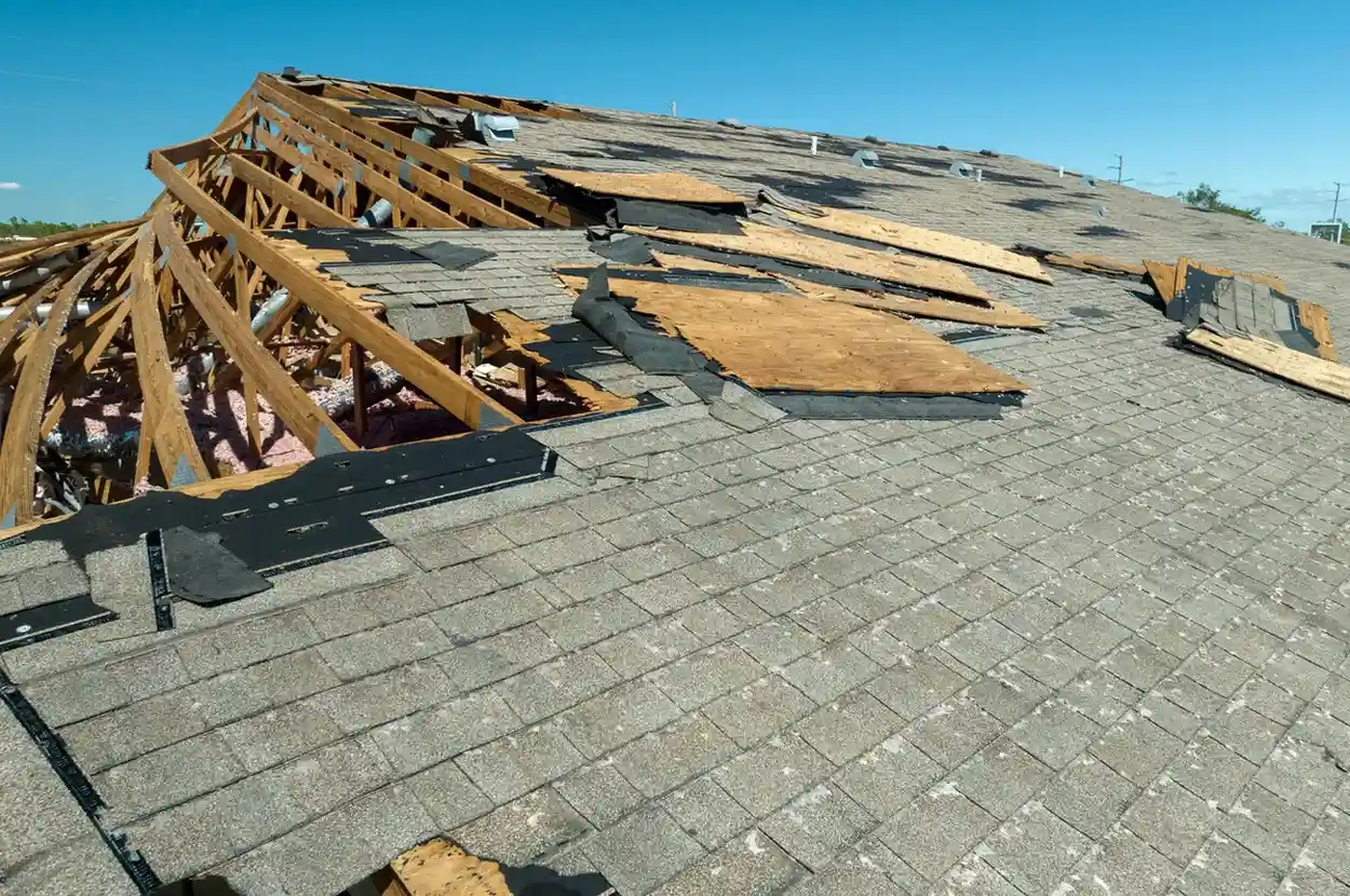 Damaged roof with exposed wooden trusses and missing shingles