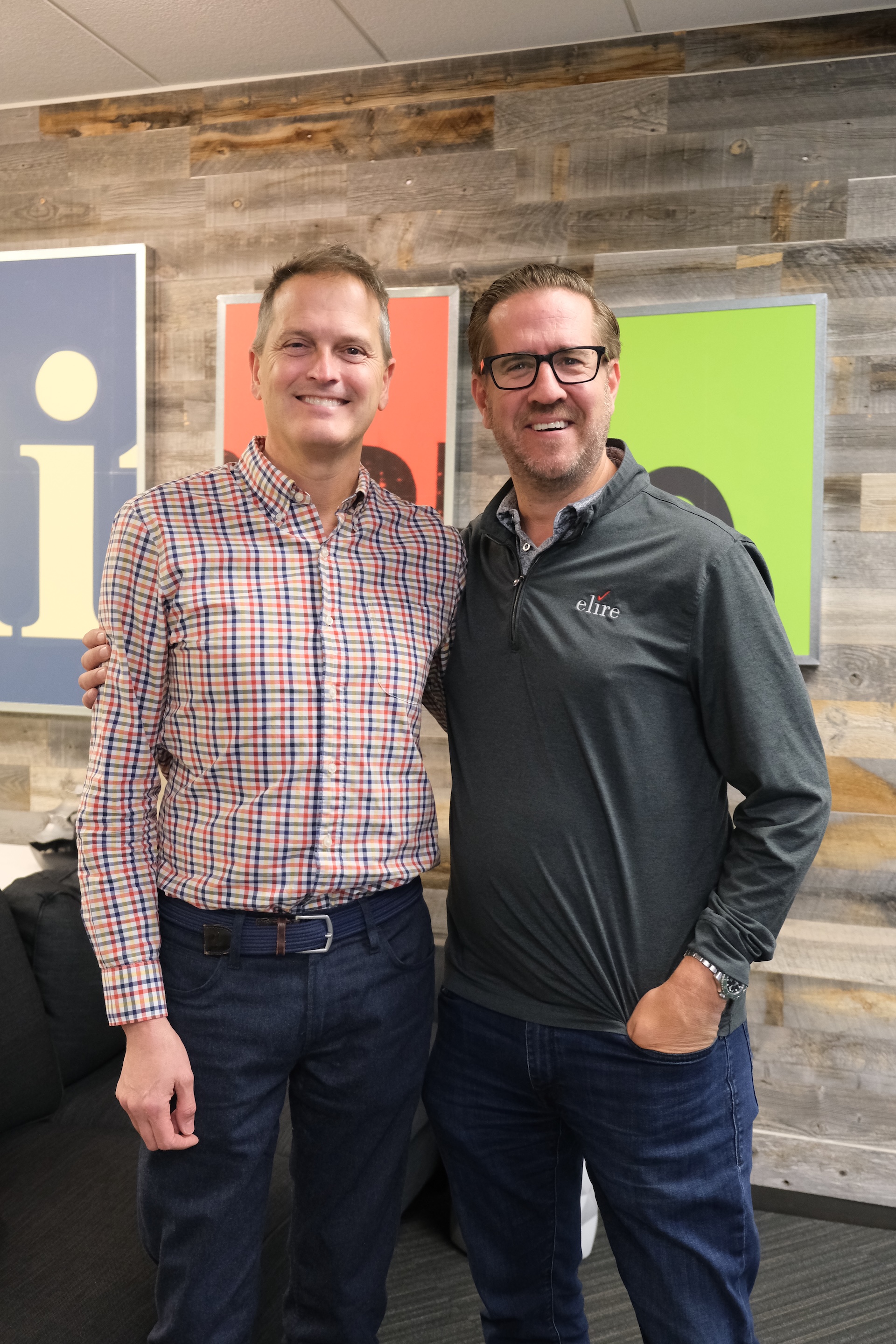 Co-CEOs of Elire Michael Merrill and Grant Bernardy smile in front of Elire sign