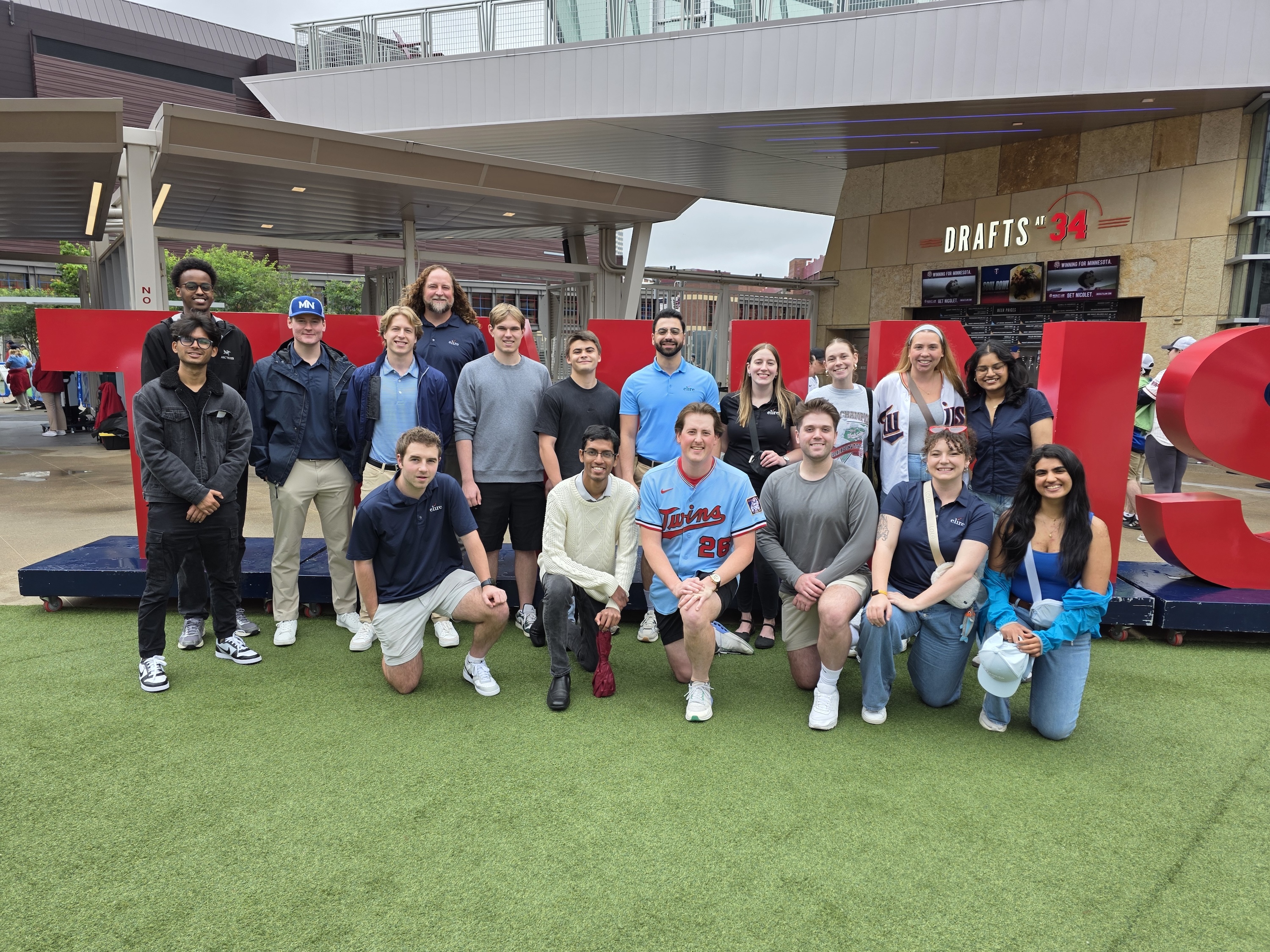 a group of people in summer clothing in front of a sign that says "twins" 