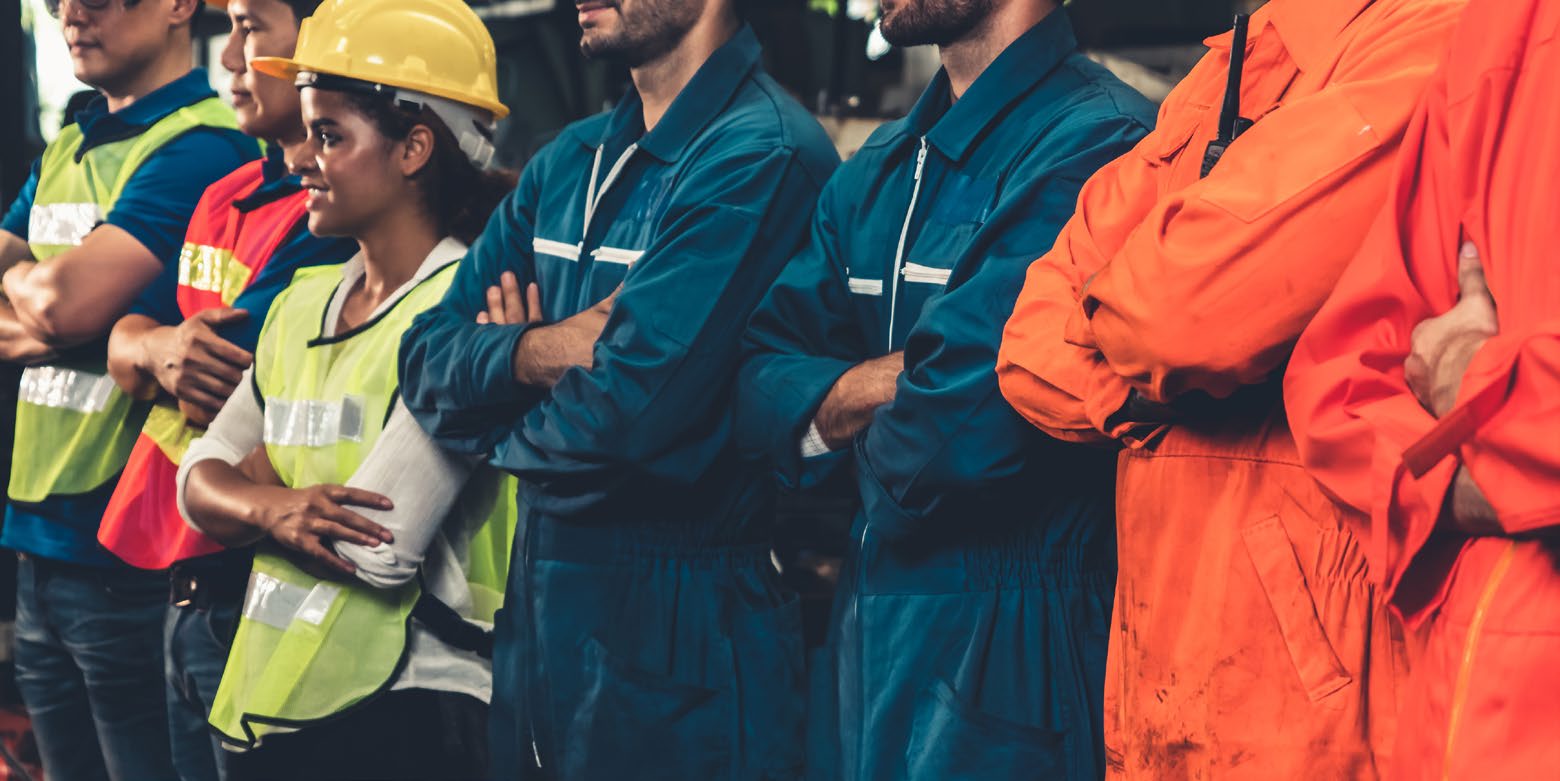 A photograph of workers wearing hardhats with crossed arms.