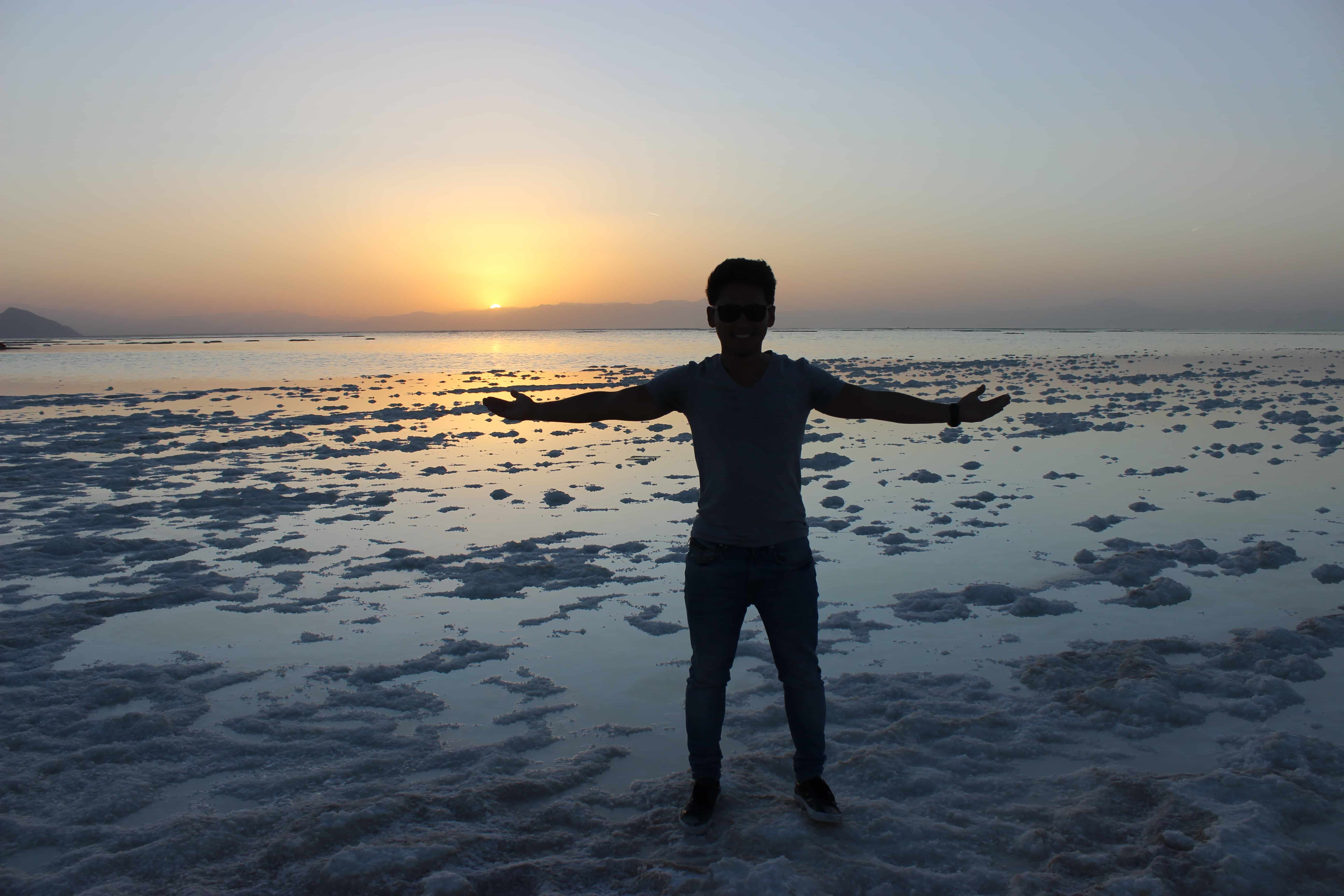 Silhouette de Kazu, les bras ouverts, devant le lac d’Ourmia au coucher du soleil en Iran.
