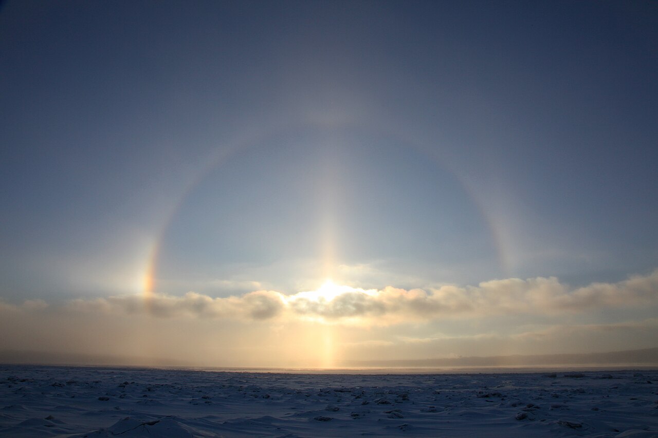 Halo solaire de 46 degrés et parhélies au-dessus d’un paysage enneigé