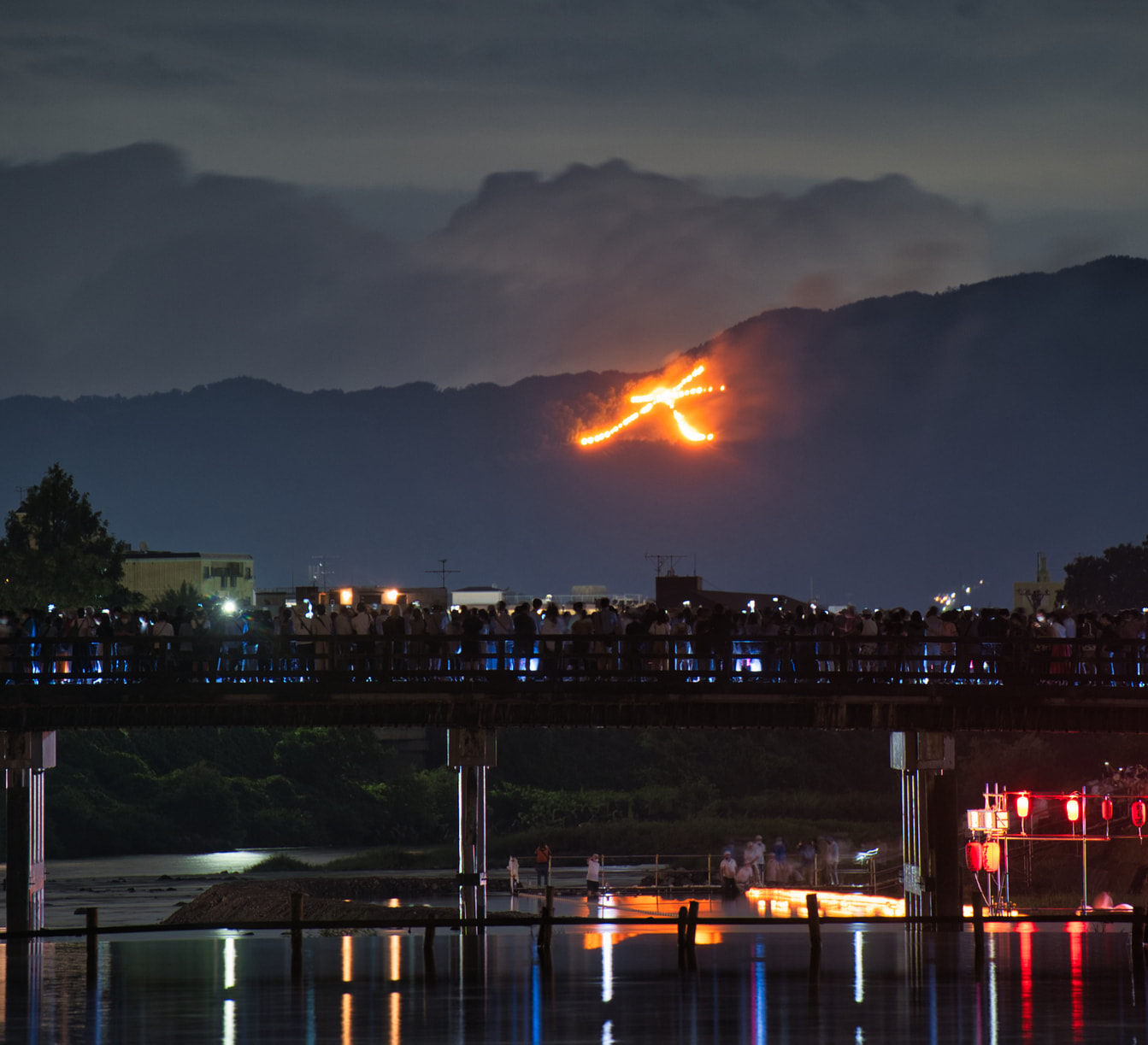 Feu du Daimonji sur une montagne de Kyoto et lanternes flottantes pendant la clôture d’Obon.