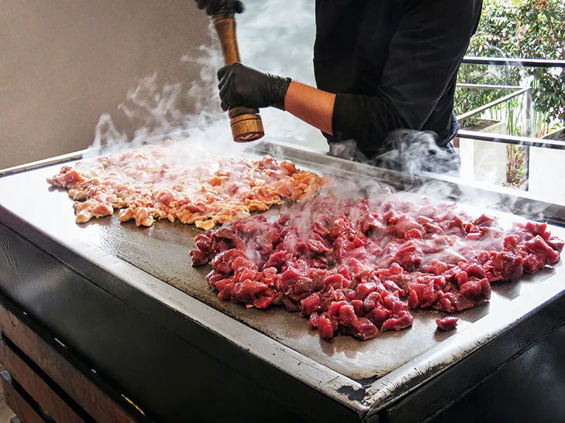 A grill with chicken and beef fillet being prepared