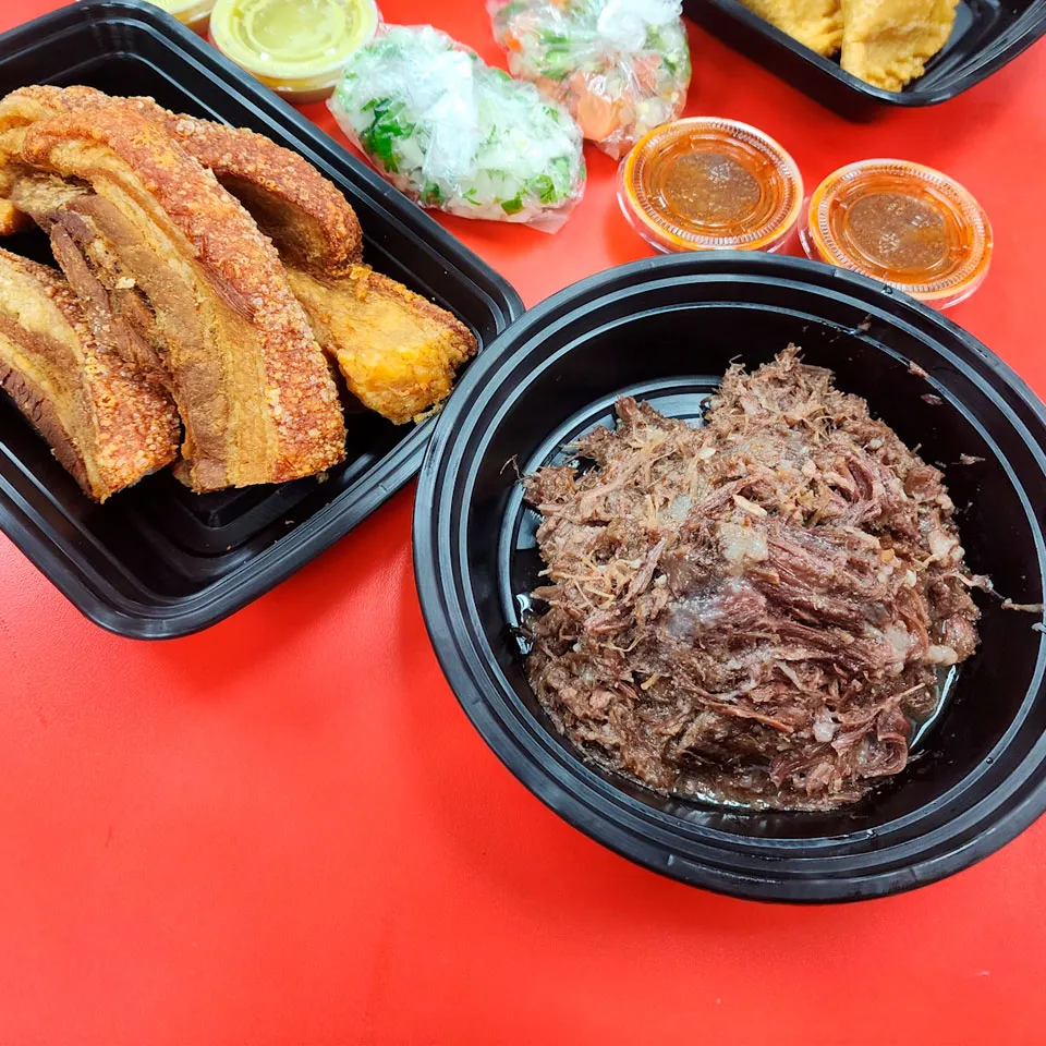 A couple of plates with barbacoa and chicharron with meat and complements aside