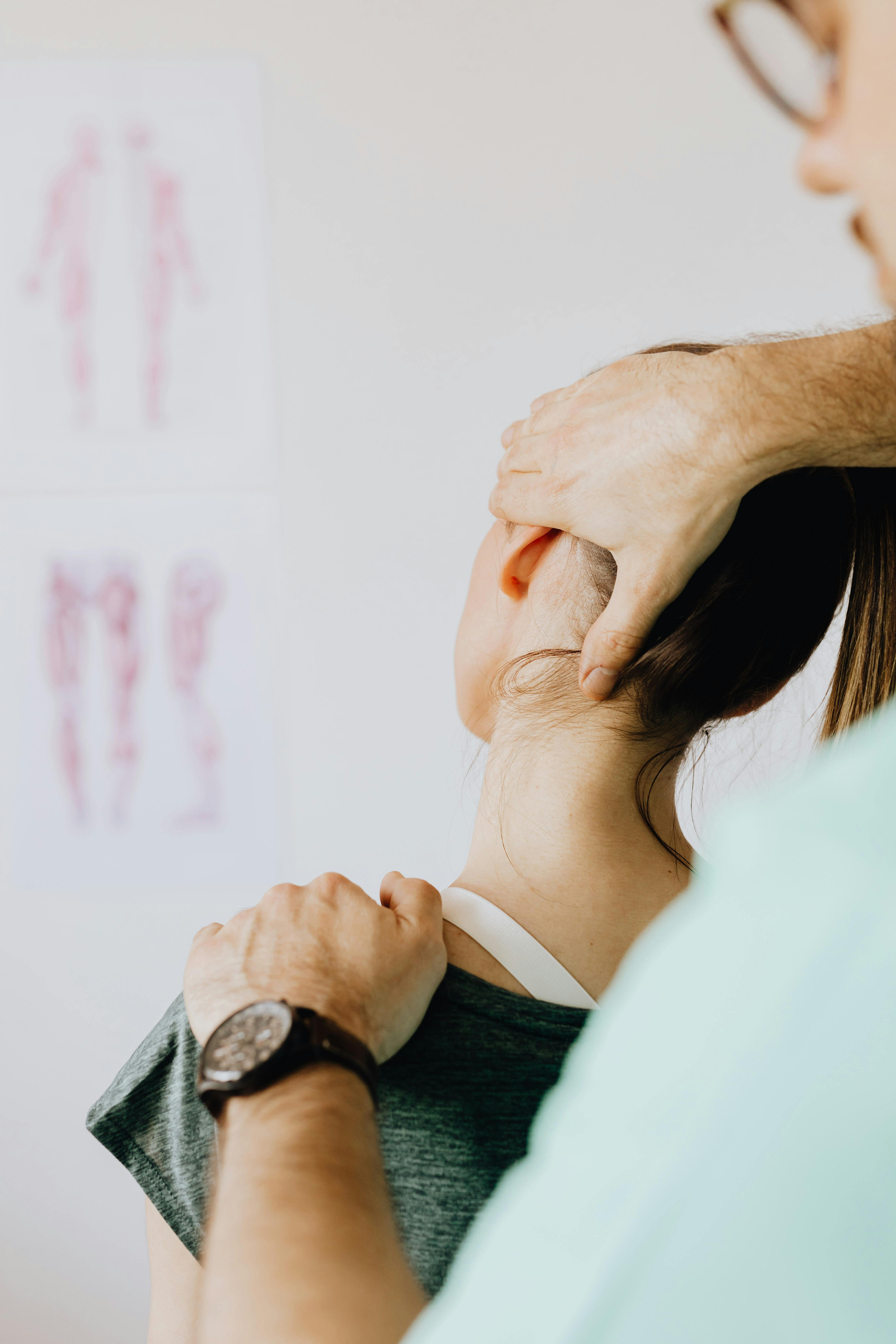 Therapist performing a neck adjustment on a woman in a clinical setting.
