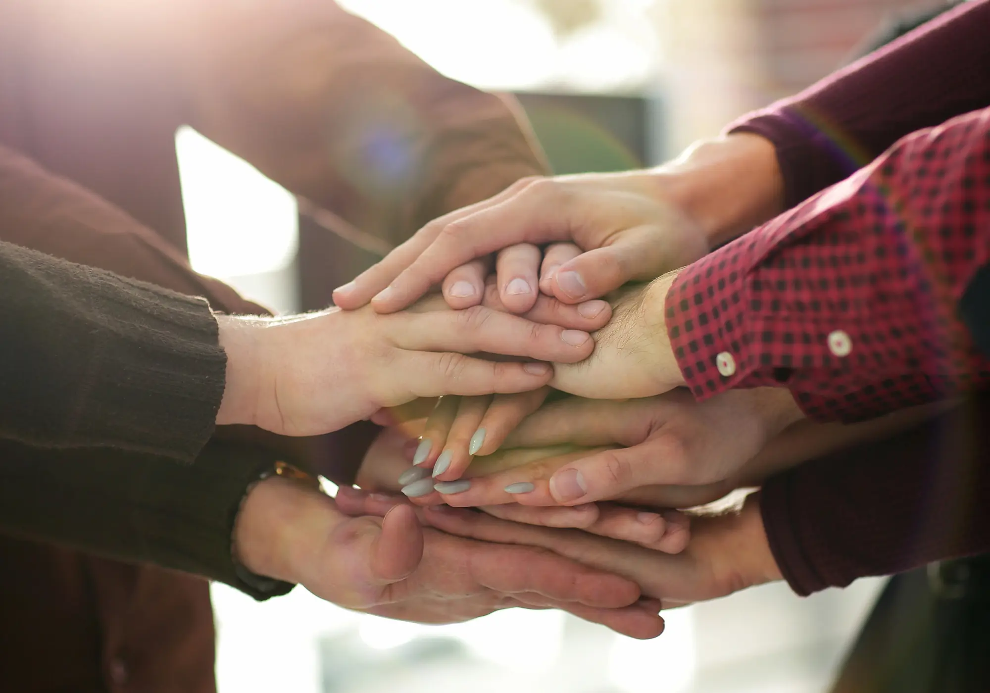 Visual metaphor for collaboration and support, showing a stack of hands from a diverse team.
