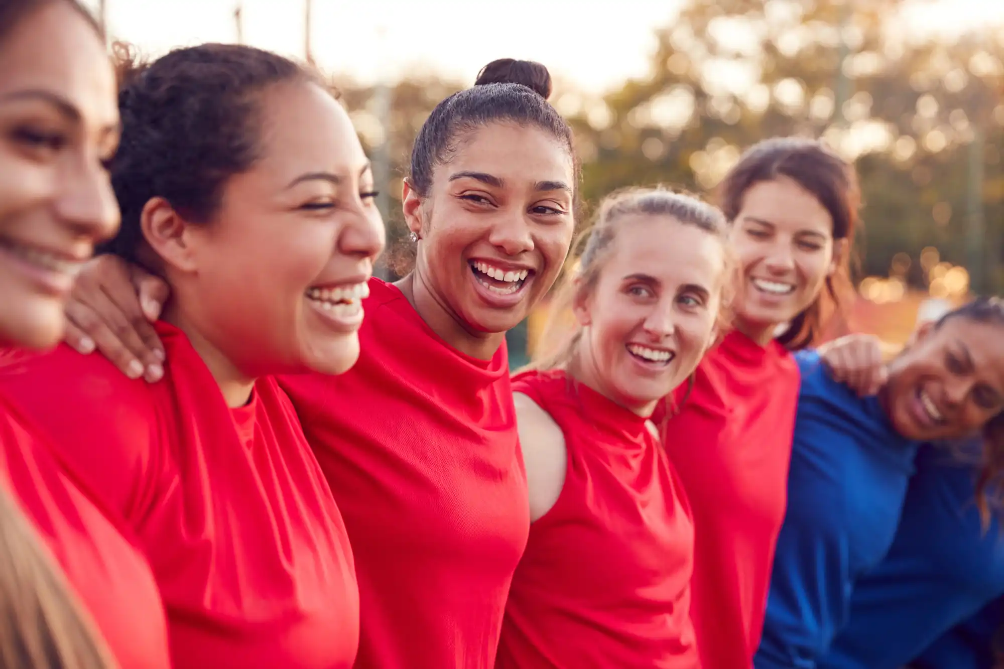 A joyful moment of camaraderie, showing a diverse women's sports team celebrating or bonding after a game.