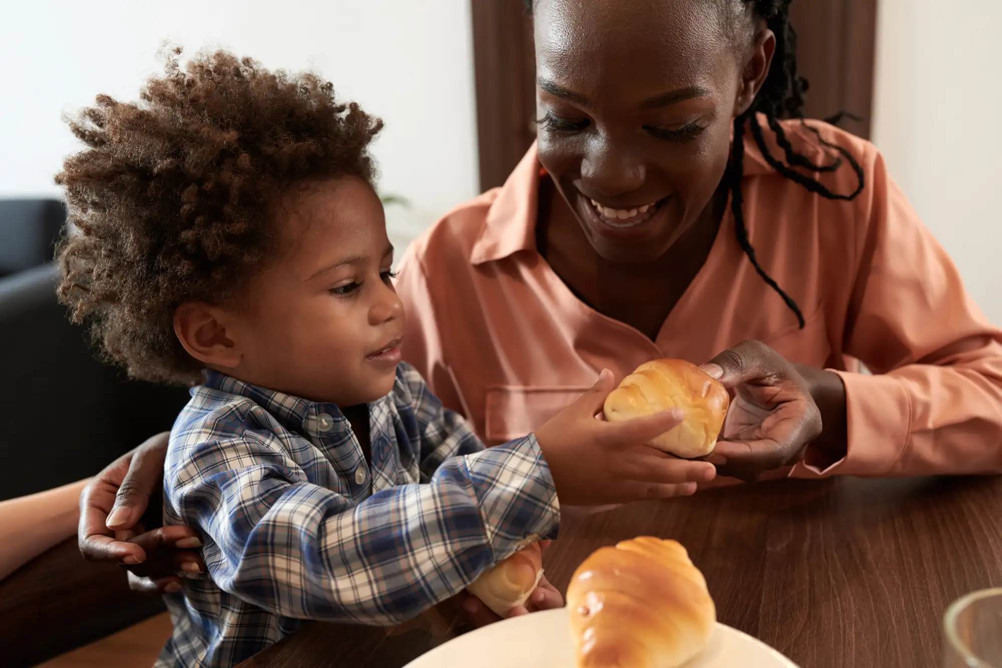 A mother and her young son sharing croissants at a table.