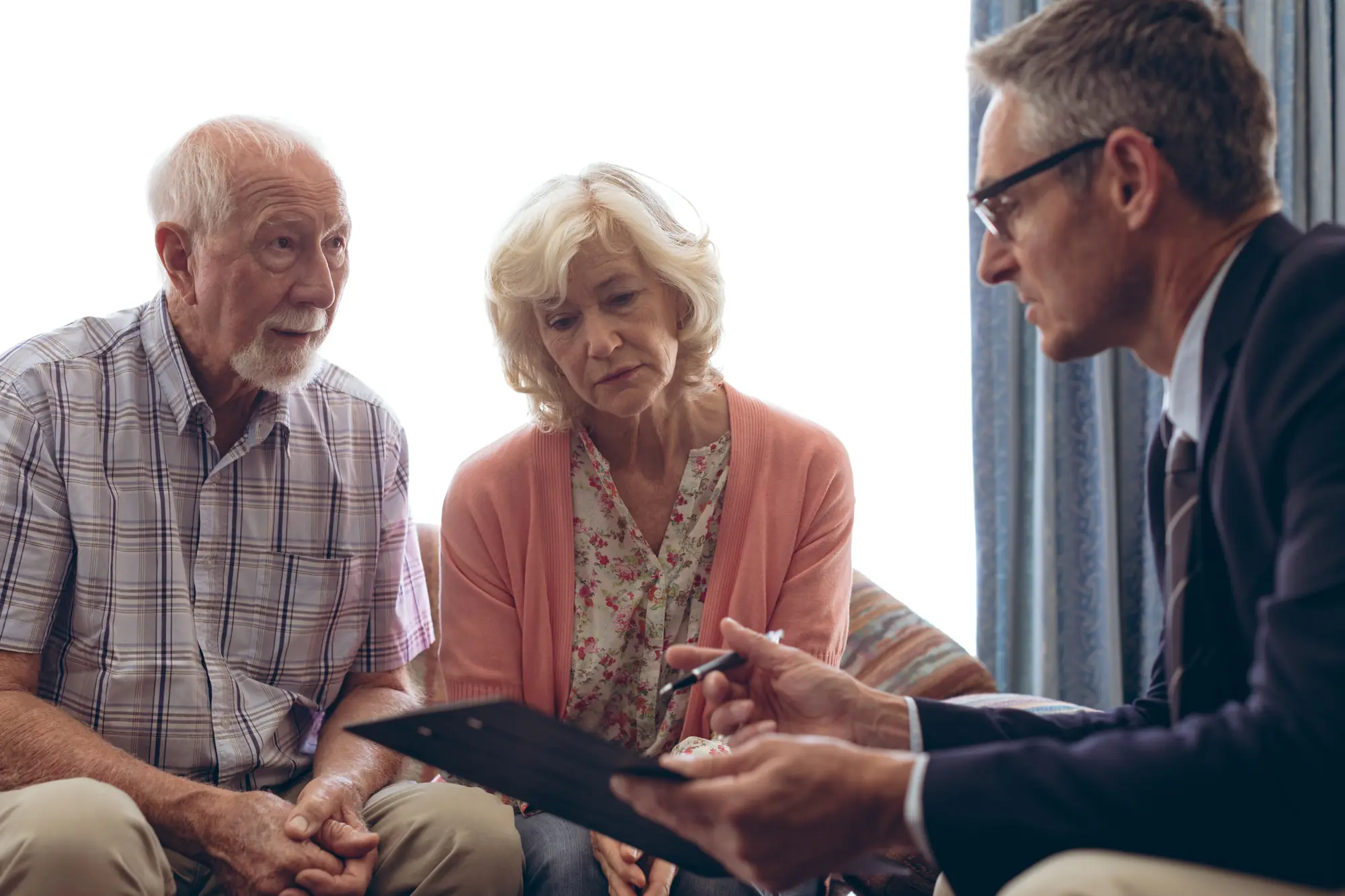 Financial advisor or lawyer discussing documents with an older couple.
