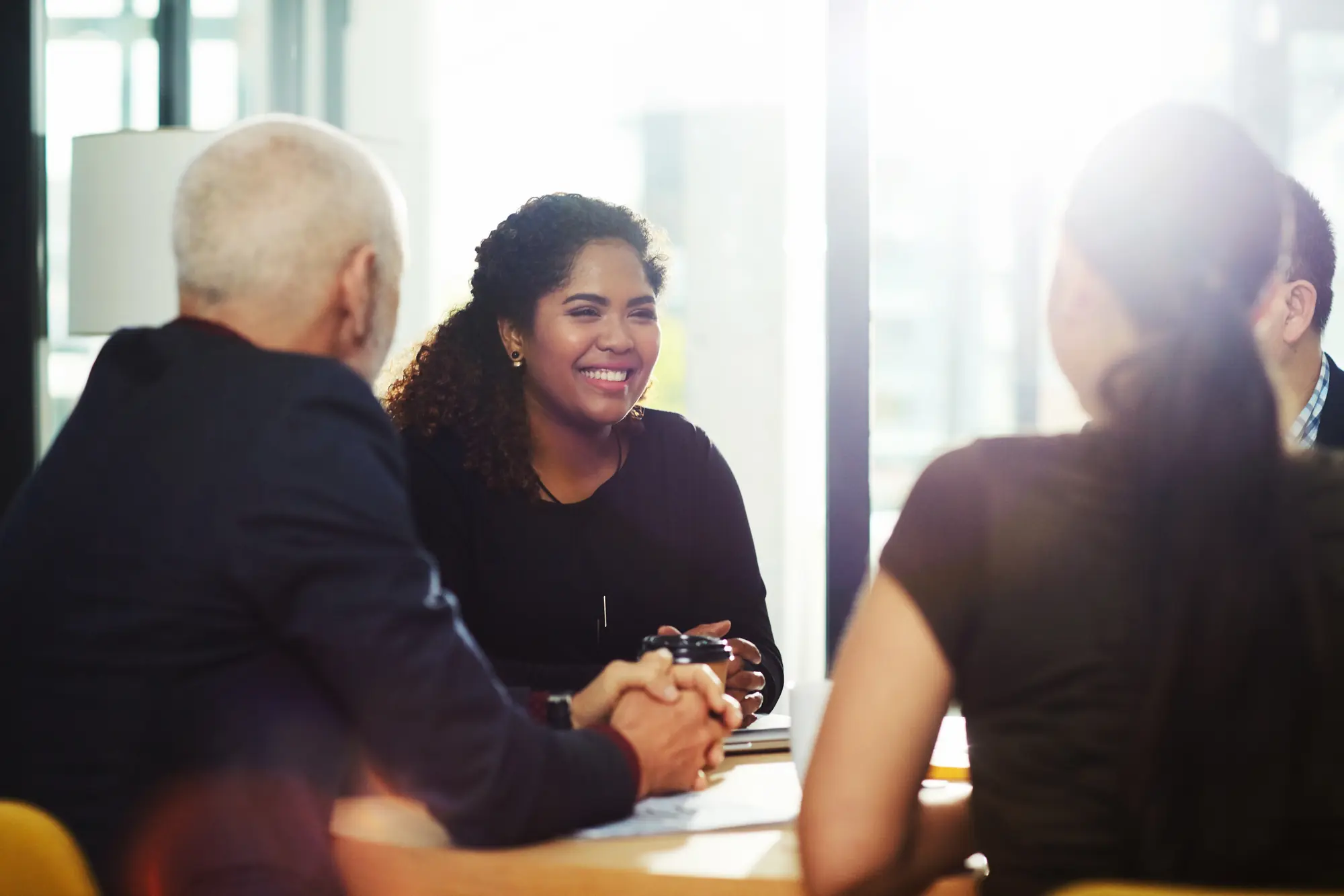 Diverse professionals having a lively discussion in a sunlit business meeting.