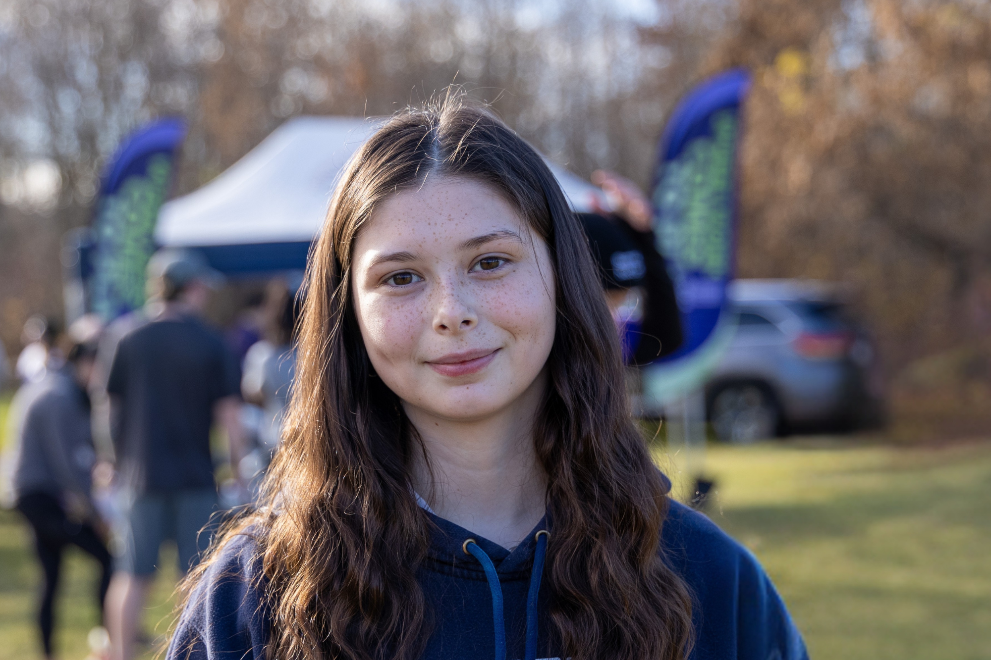 Smiling teenage girl with long brown hair at an outdoor fundraising event