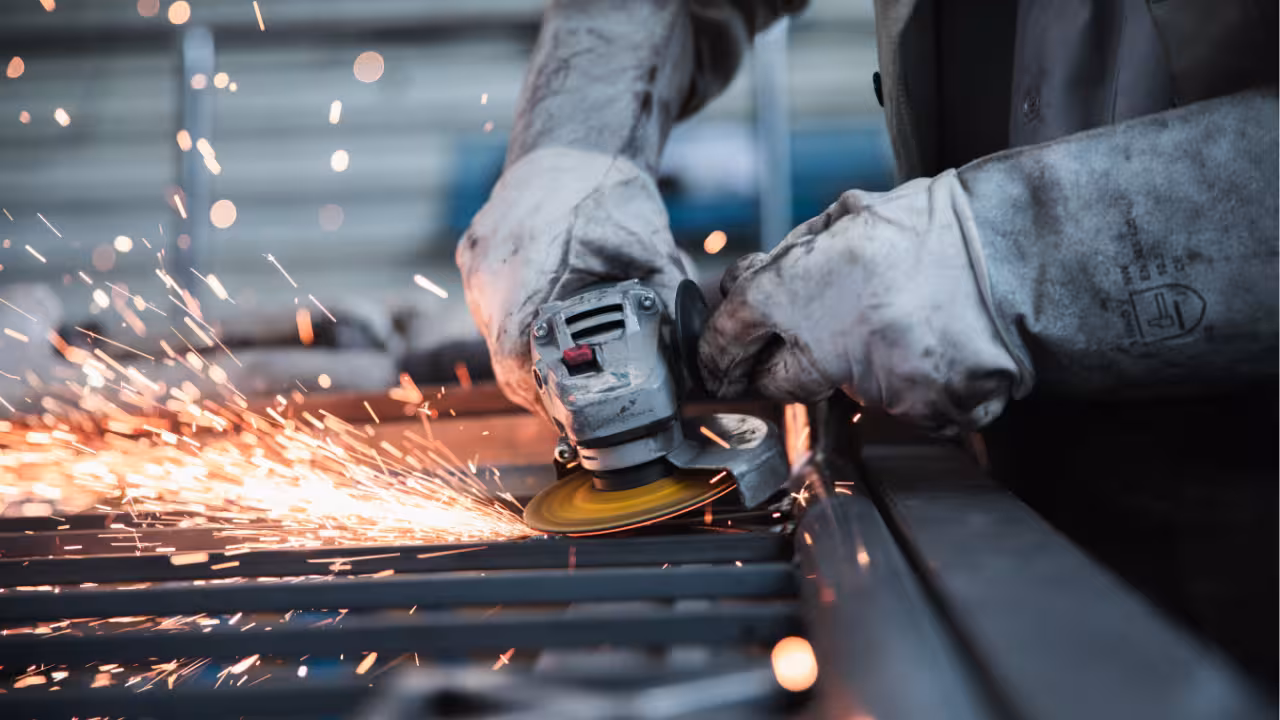 Worker using an angle grinder with sparks flying in a metal workshop