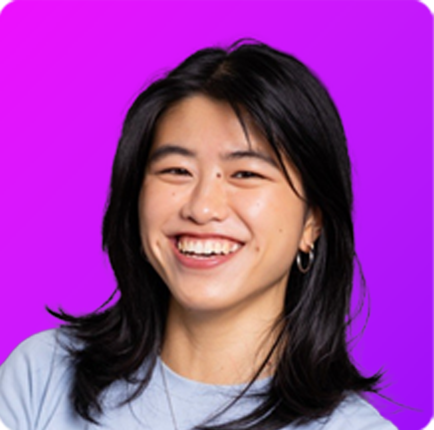 Smiling young man with glasses and dreadlocks wearing a light beige sweater against a bright blue gradient background.