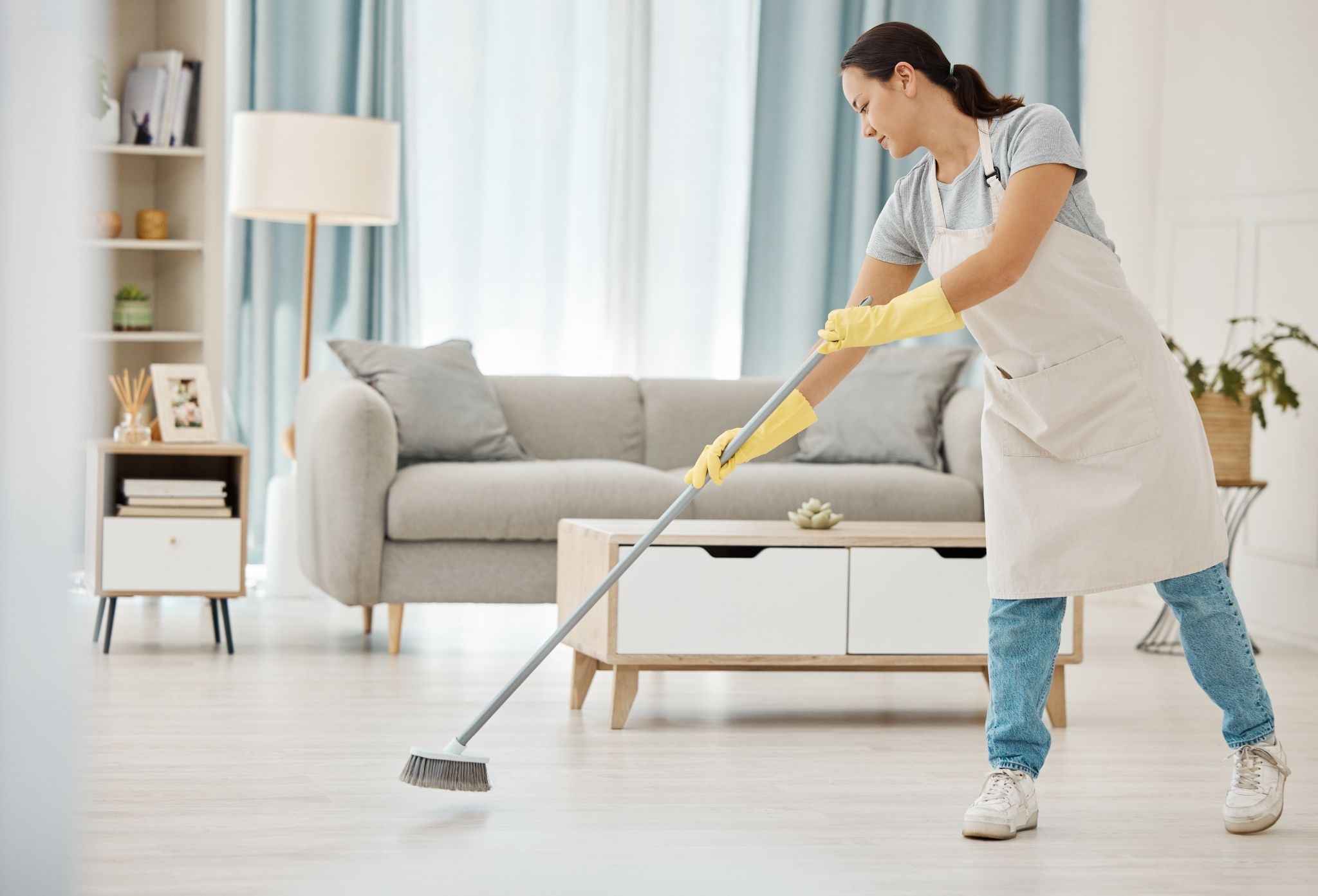 Cleaner sweeping a living room floor for Airbnb maintenance.