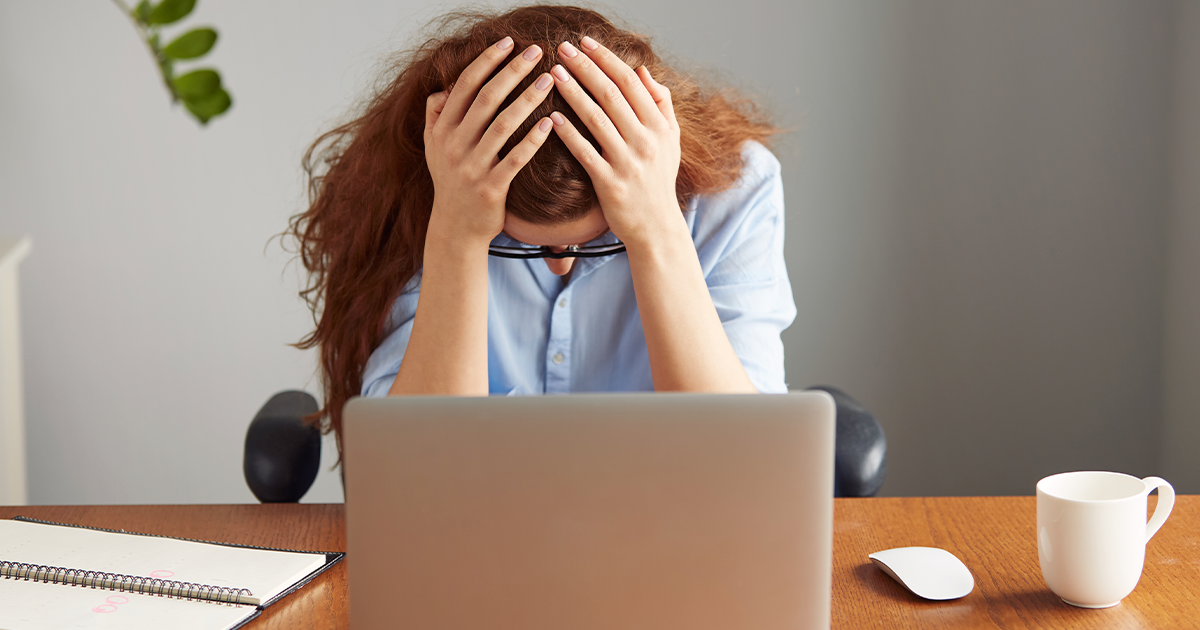 Frustrated independent worker sits in front of her laptop feeling burned-out from working