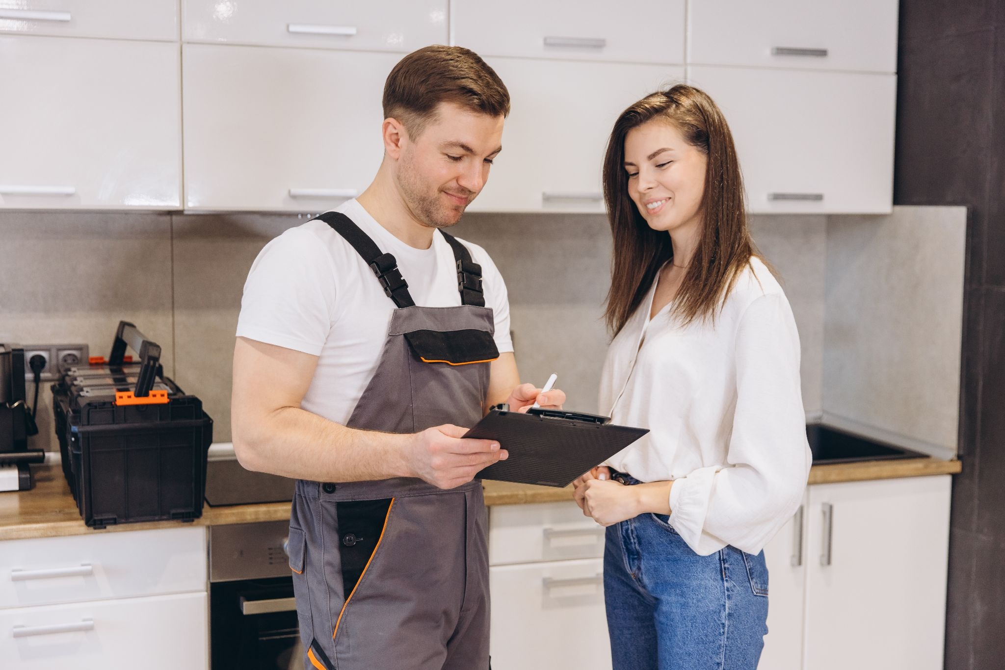A service pro discussing his prices with a client while standing in front of her kitchen sink.