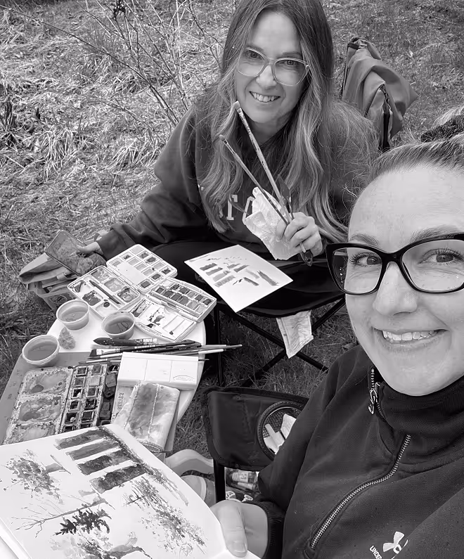 two women sitting outside painting