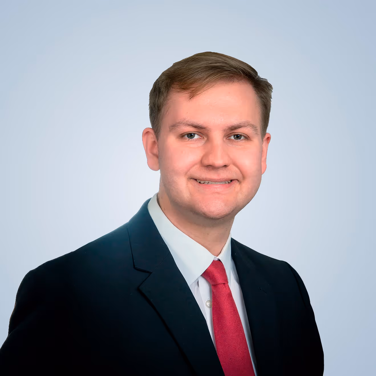 Mason Lefoer, office administrator of Allied Wealth Planners, posing with a smile and a suit.