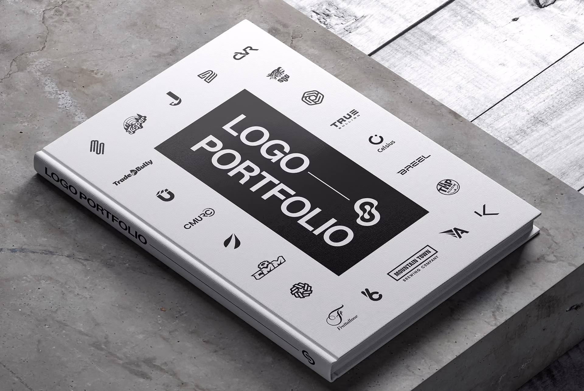 A coffee table book titled Logo Portfolio is centered on the front cover, while various black logos surround it. The book is placed on top a concrete surface, and the cover features a clean, modern design.