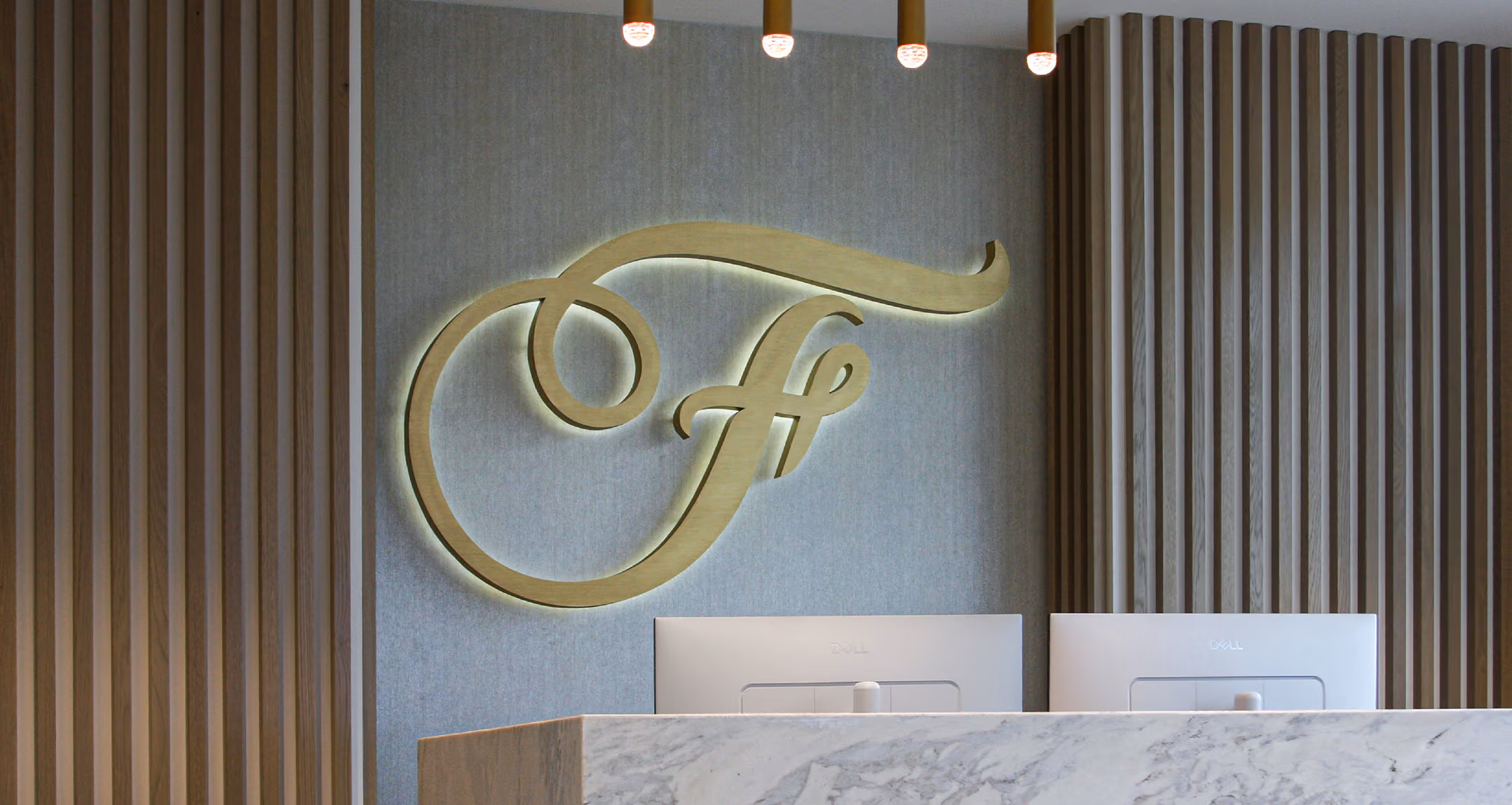 Frattallone Wealth Partners gold logo behind the marble reception desk.